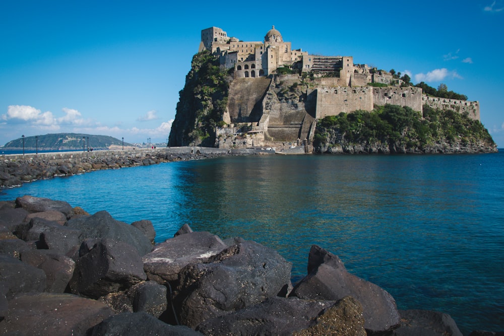 a large castle sitting on top of a mountain next to a body of water