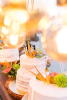 A joyful baker placing finishing touches on a tiered wedding cake in a bright kitchen.