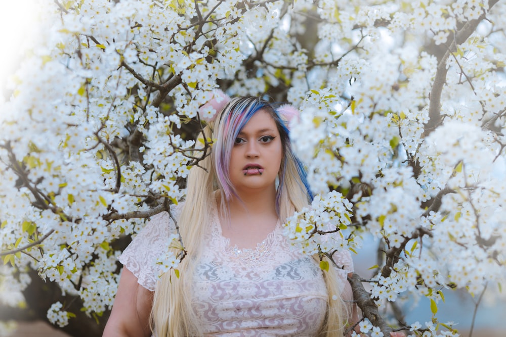 a woman with blue hair standing in front of a tree