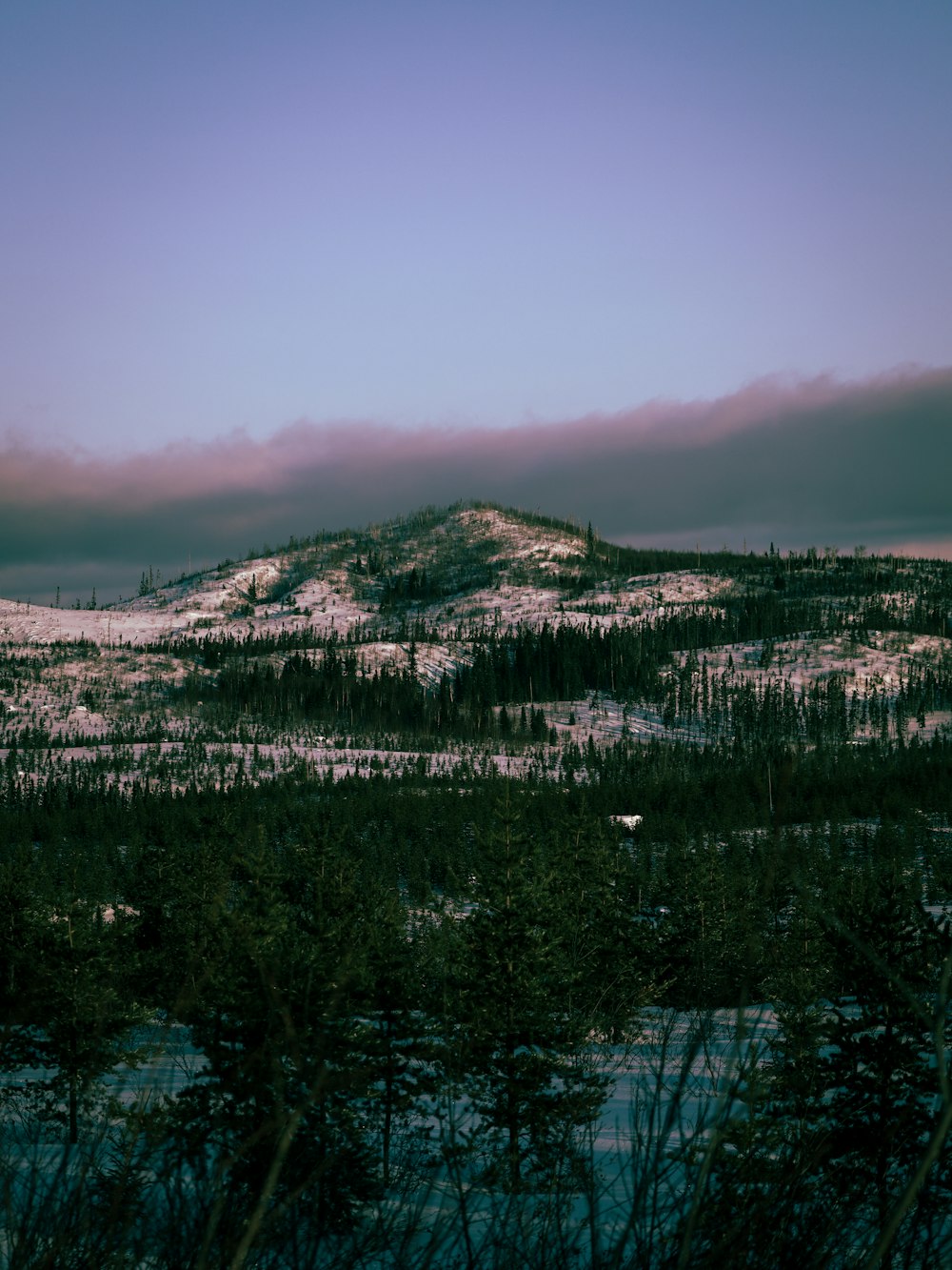 a mountain covered in snow under a cloudy sky