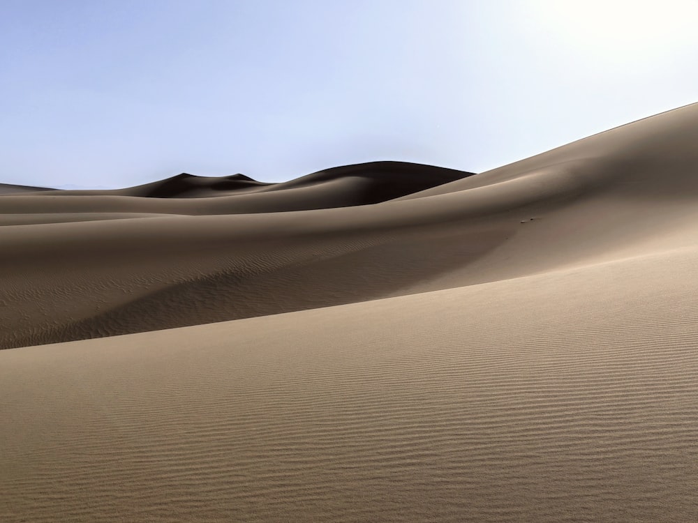 a desert with sand dunes and a blue sky