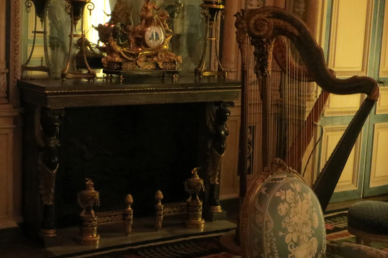 A period room with an original fireplace and a harp standing beside the chimney breast.