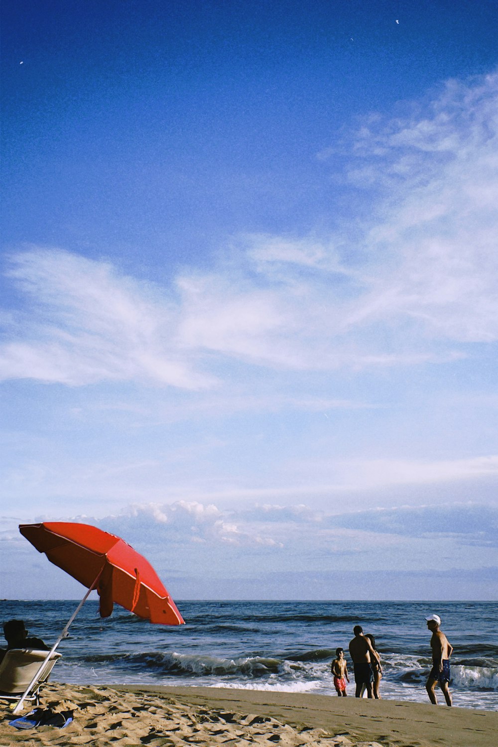 a red umbrella sitting on top of a sandy beach