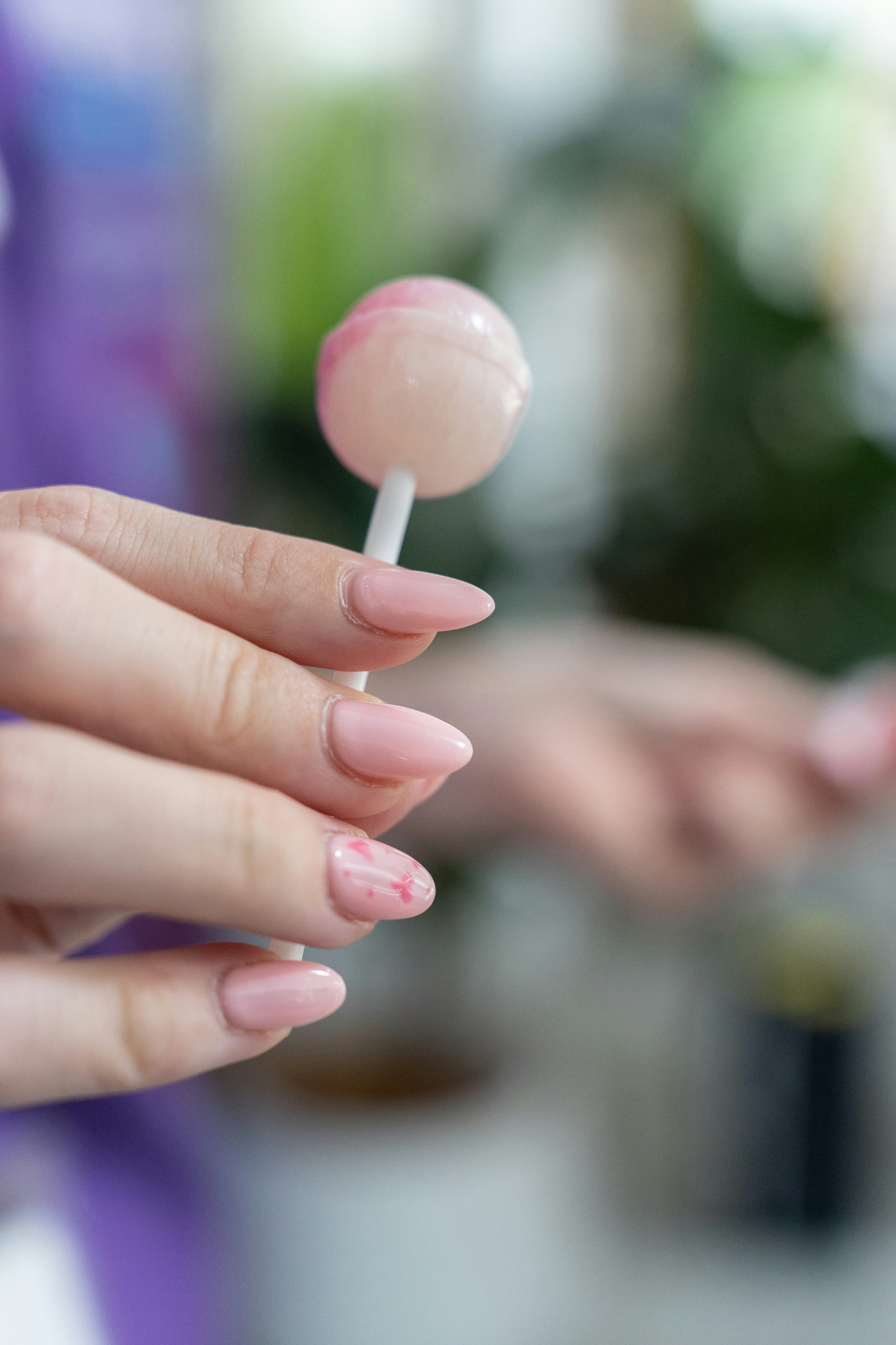 Una mujer sosteniendo una piruleta rosa en la mano