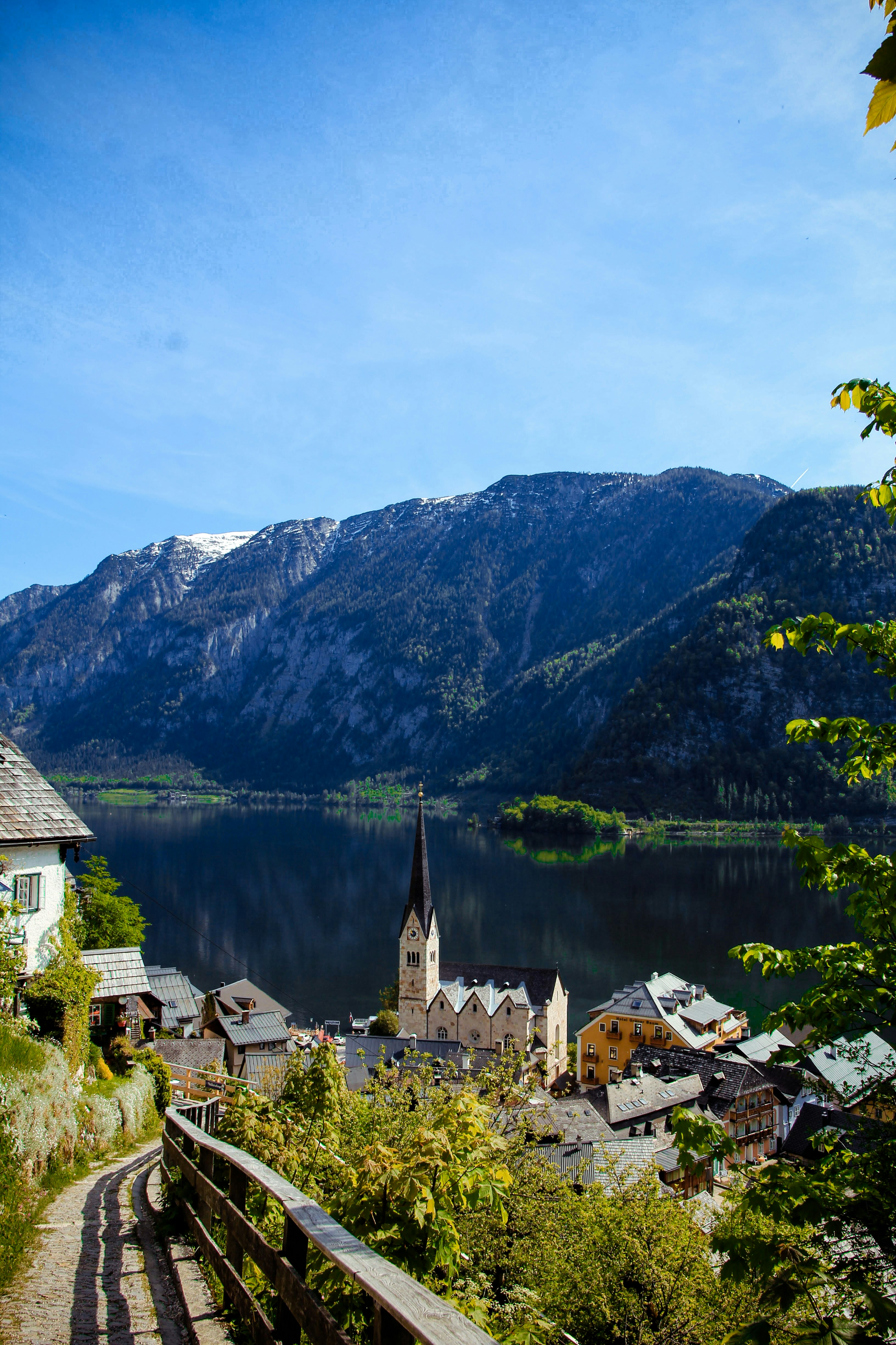 a scenic view of a small town with a lake and mountains in the background