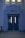 A blue double door with vertical rectangular windows, labeled 'GIRLS' above. The building facade has classical-style architecture with decorative elements in the same blue color. Two windows are visible above the label and emit a warm glow. Attached to the left door is a sign with a 'STOP' hand graphic in red.