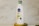 A white bottle of Nivea Naturally Good body lotion with a blue cap is placed on a wooden surface. The label indicates the product contains natural oats and is 98% natural origin ingredients. The background features a light marble surface.