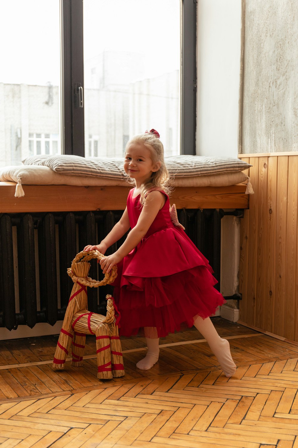 a little girl in a red dress holding a stuffed animal