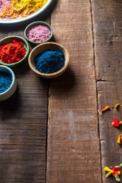 Hand holding a decorative bowl filled with colorful Ayurvedic powders.
