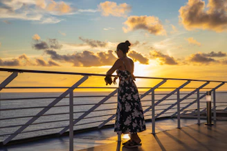 a woman standing on a deck looking out at the ocean