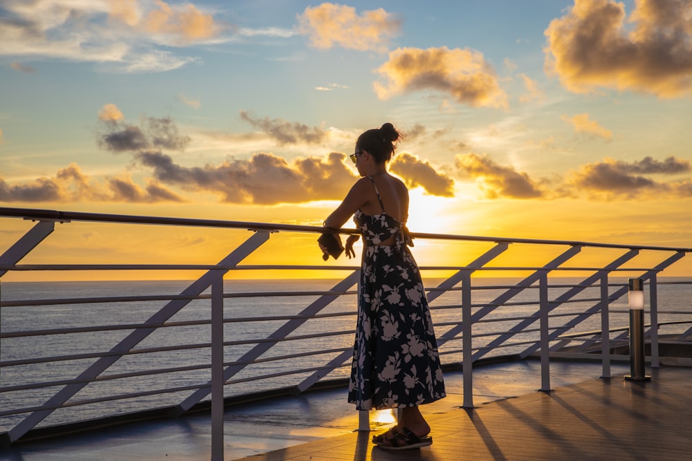 a woman standing on a deck looking out at the ocean