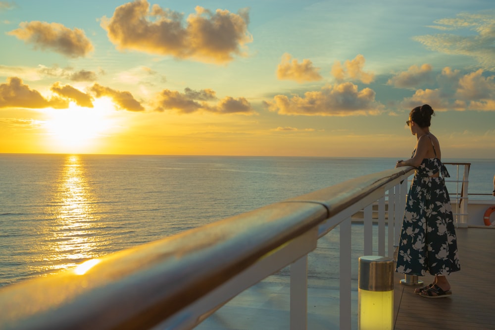 a woman standing on a deck looking out at the ocean