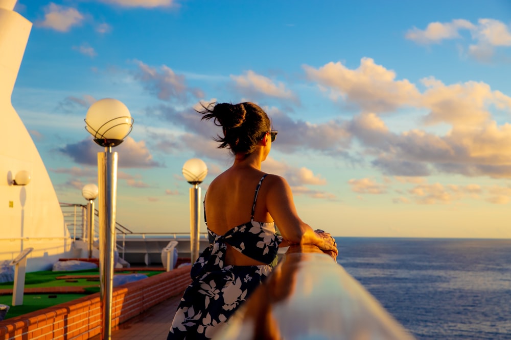 a woman standing on a balcony looking out at the ocean