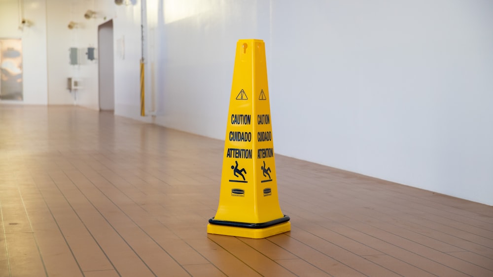 a yellow caution cone sitting on top of a hard wood floor