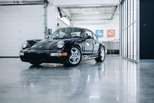 A shiny, freshly painted car parked in a clean garage under bright lights.