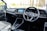 The interior of a car with a focus on the driver's area, featuring a modern steering wheel with a logo in the center, a sleek dashboard with a digital display showing several app icons, and minimalistic controls.
