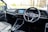 The interior of a car with a focus on the driver's area, featuring a modern steering wheel with a logo in the center, a sleek dashboard with a digital display showing several app icons, and minimalistic controls.