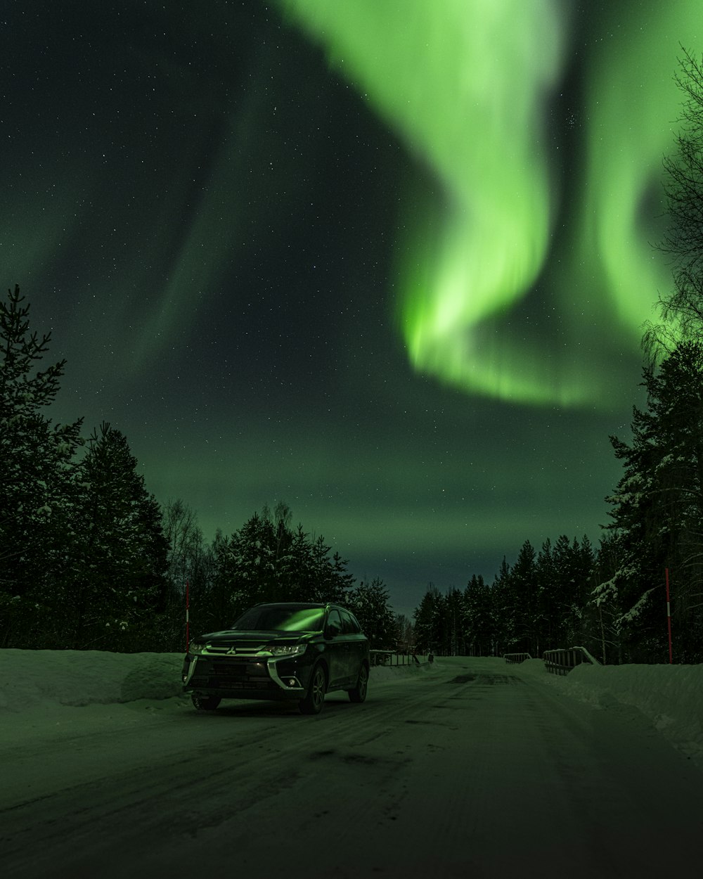 a car driving down a snow covered road under a green light