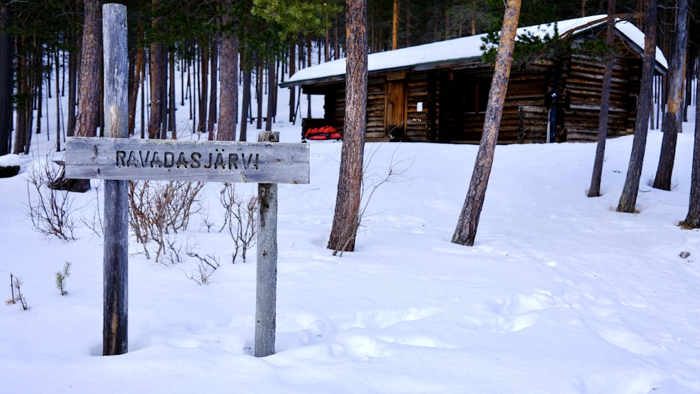 Un letrero en la nieve cerca de una cabaña