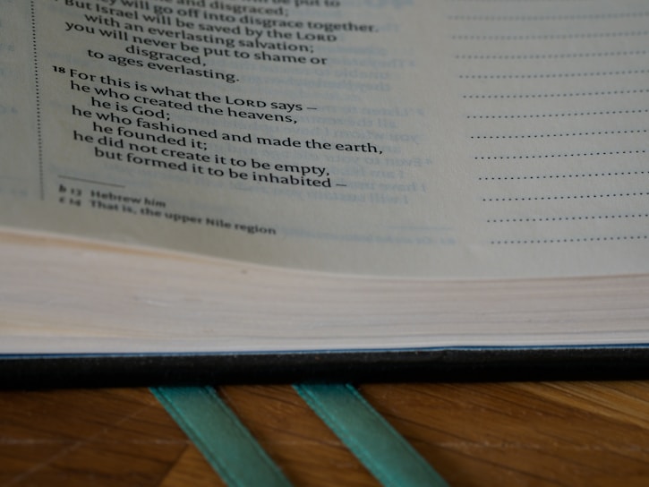 Close-up of an open book with highlighted text on a wooden table.
