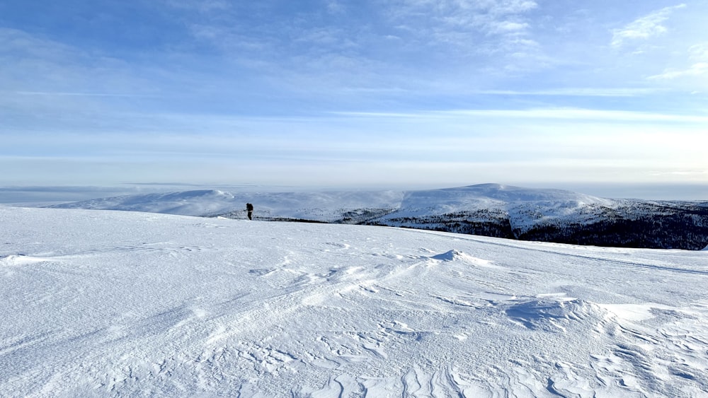 Una persona parada en la cima de una pendiente cubierta de nieve