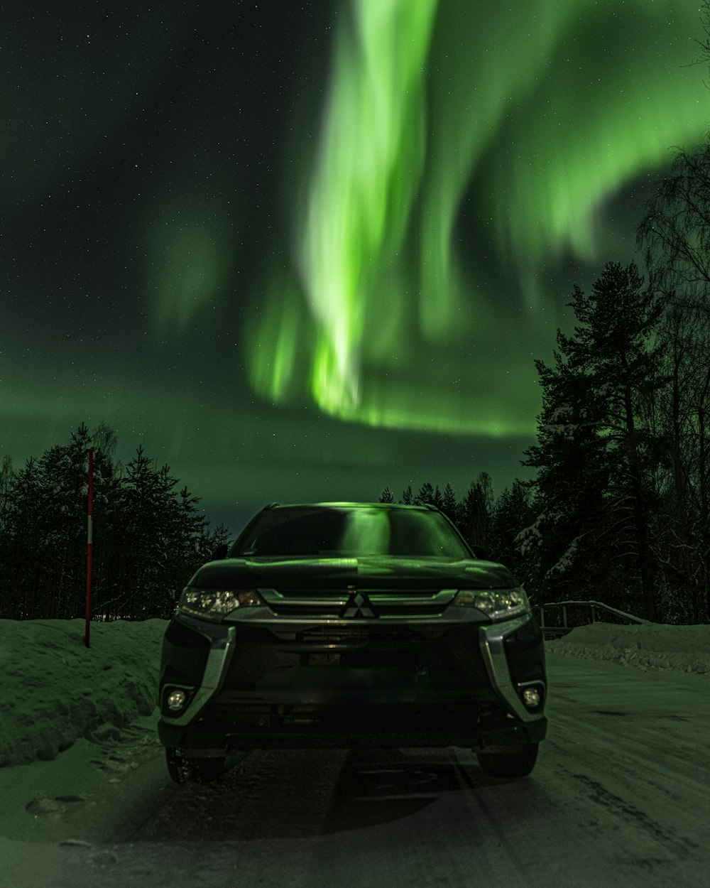 a car driving down a snow covered road under a green light