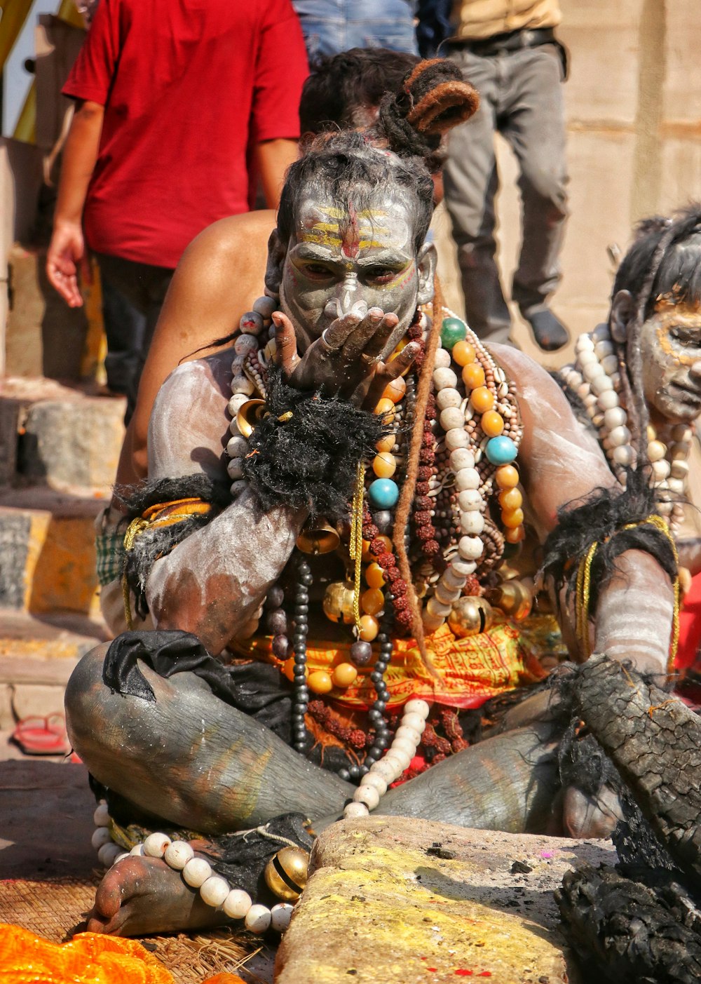 a man with painted face and body sitting on the ground