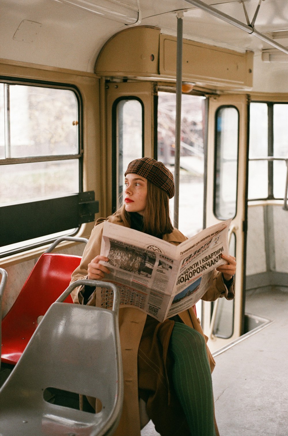 a woman sitting on a bus reading a newspaper