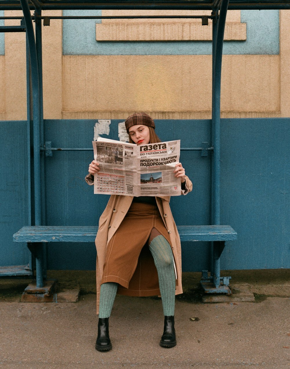 a woman sitting on a bench reading a newspaper