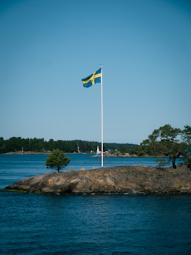 a flag on a rock in the middle of a lake