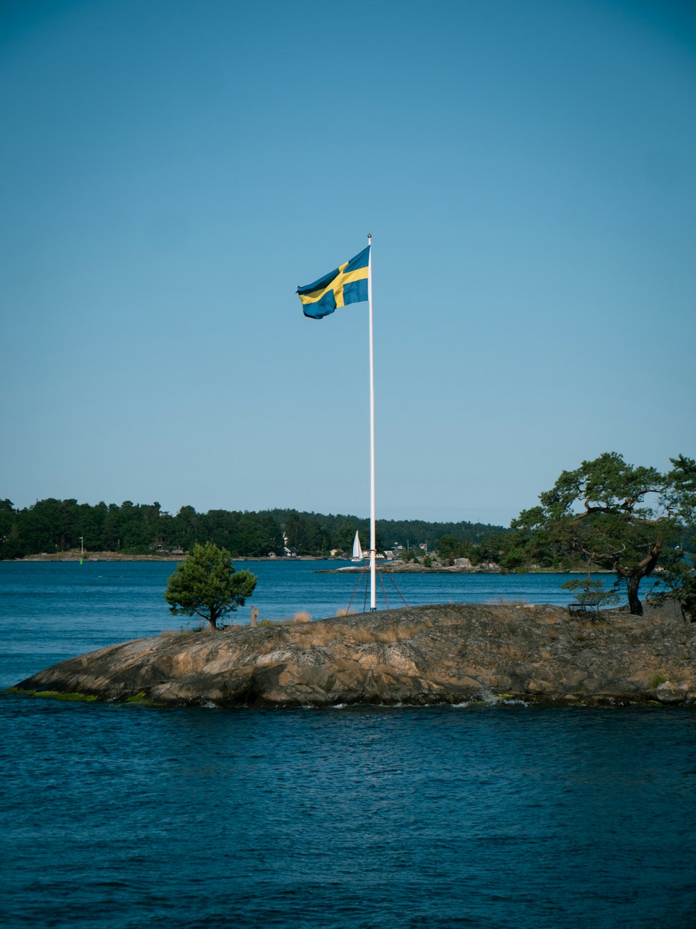 a flag on a rock in the middle of a lake
