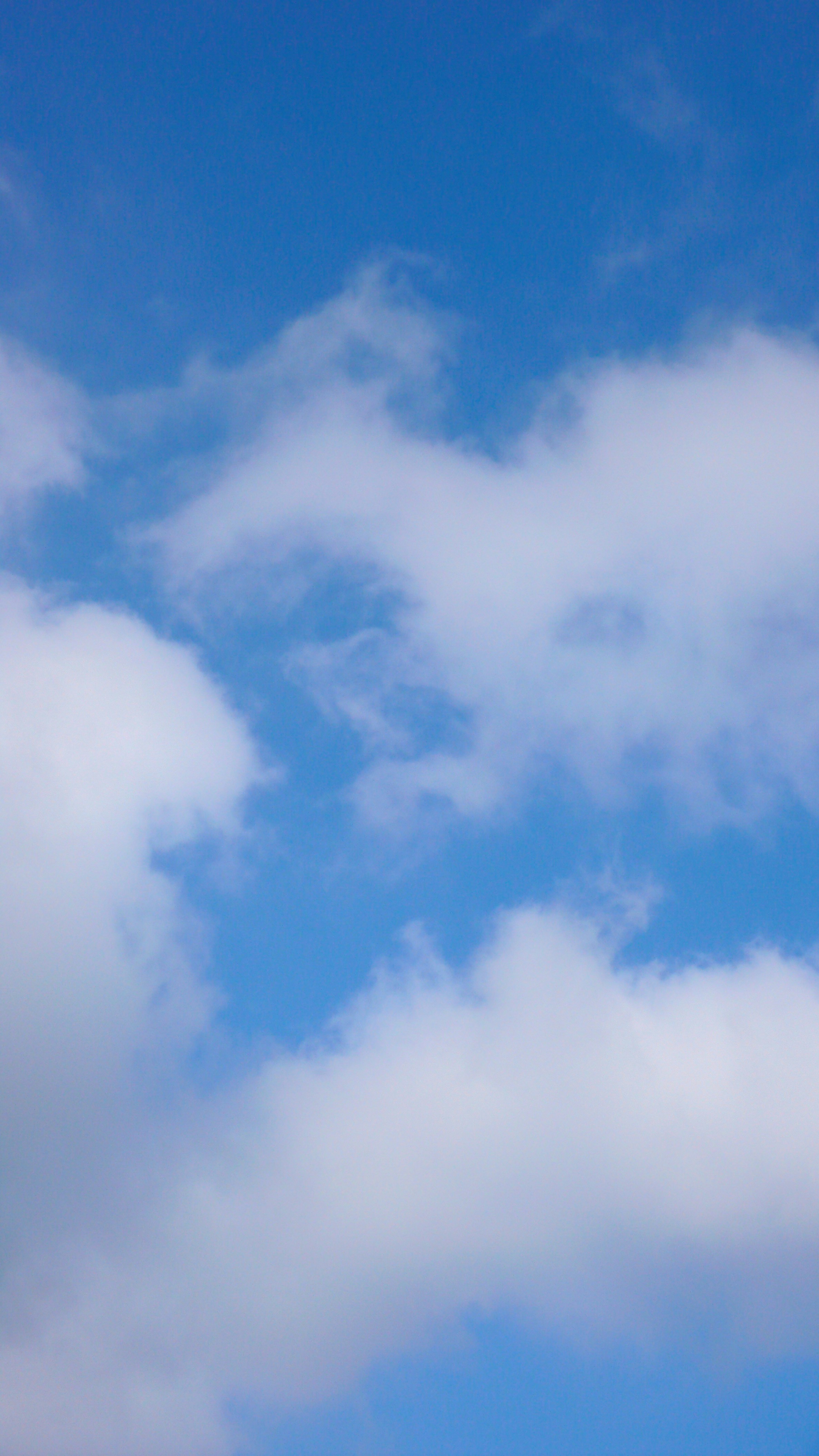 a plane flying through a blue cloudy sky