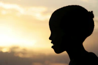 A toddler's silhouette framed by the golden light of a late afternoon.