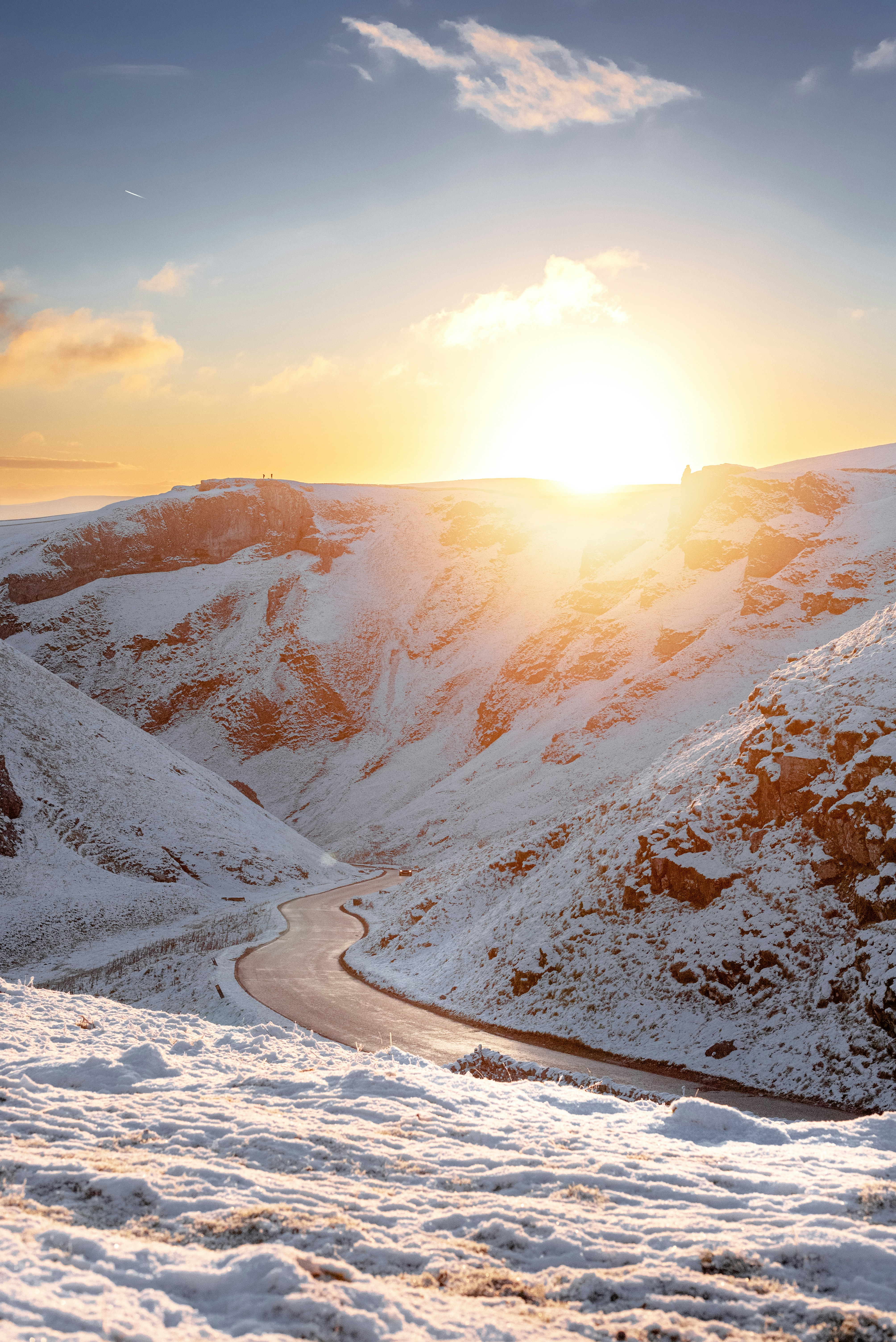 the sun is setting over a snowy mountain