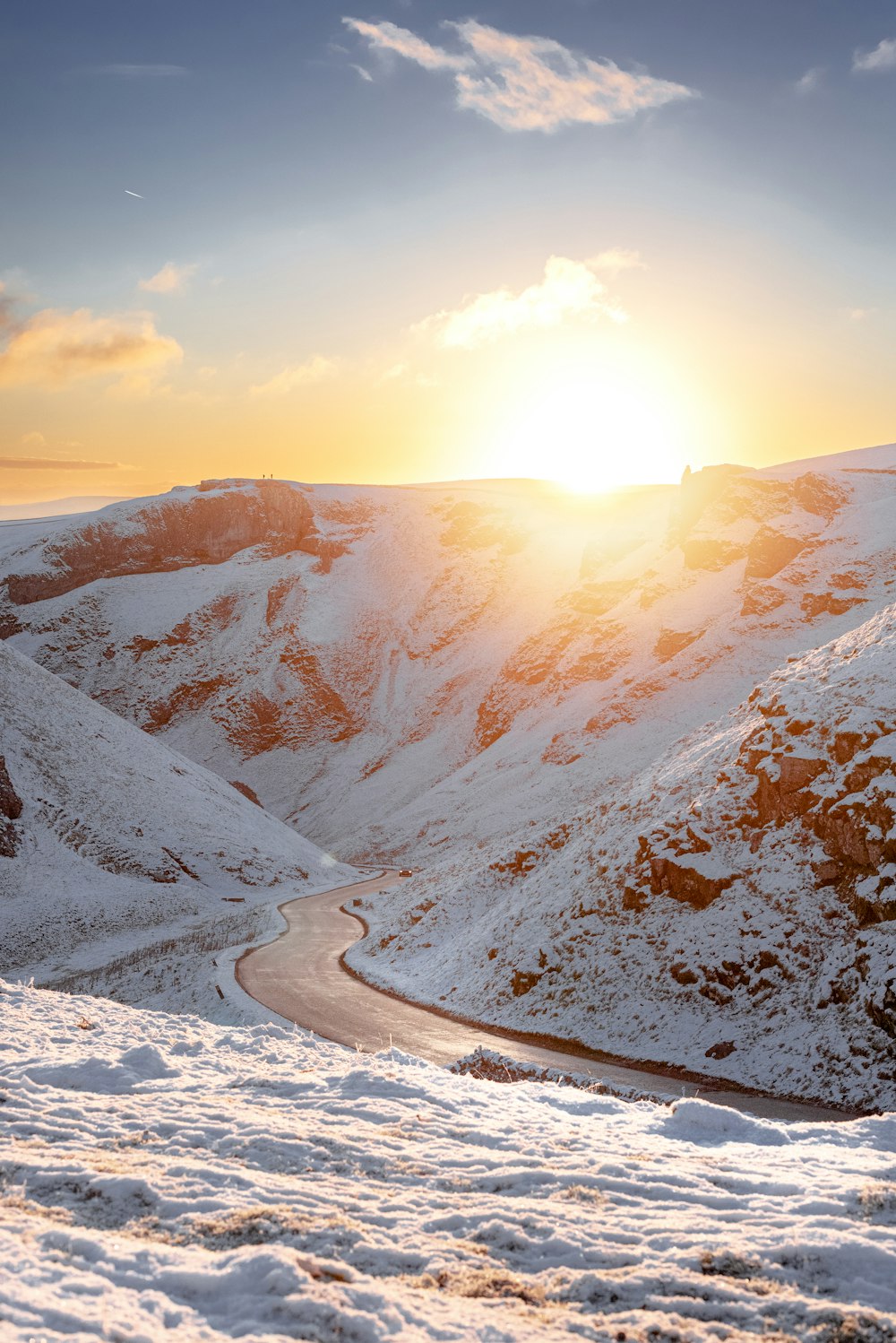 the sun is setting over a snowy mountain