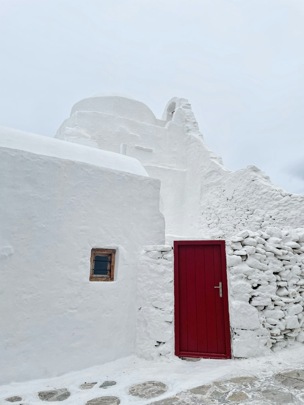 Une porte rouge est ouverte sur un bâtiment blanc