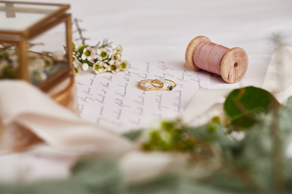 two wedding rings and a spool of thread on a table