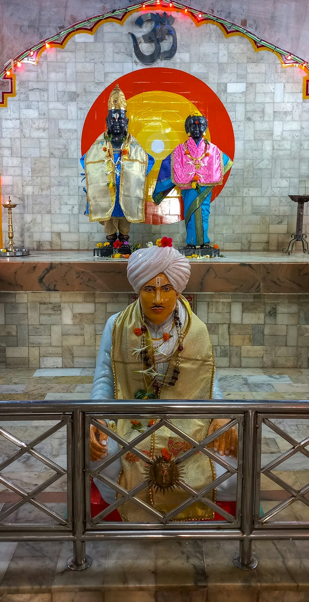 a man with a turban sitting in front of a statue