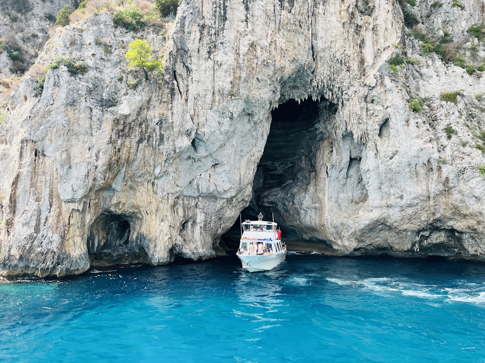 a boat in the water near a large rock formation