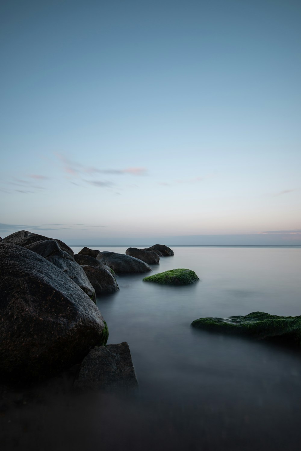 a long exposure of the ocean with rocks in the foreground