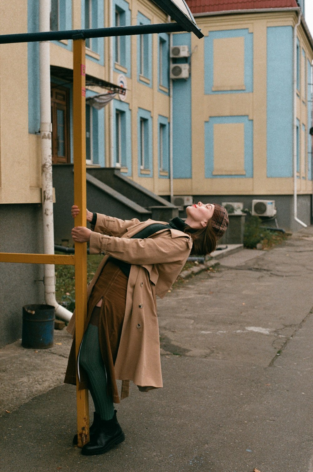 a woman leaning against a pole on a city street