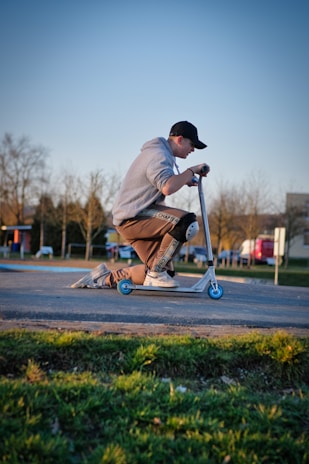 A rider wearing a Scootin My Way hoodie cruising down a sunny city street.