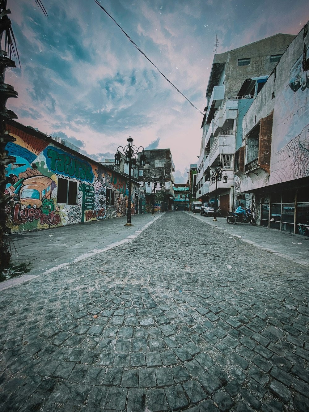 a cobblestone street with graffiti on the buildings