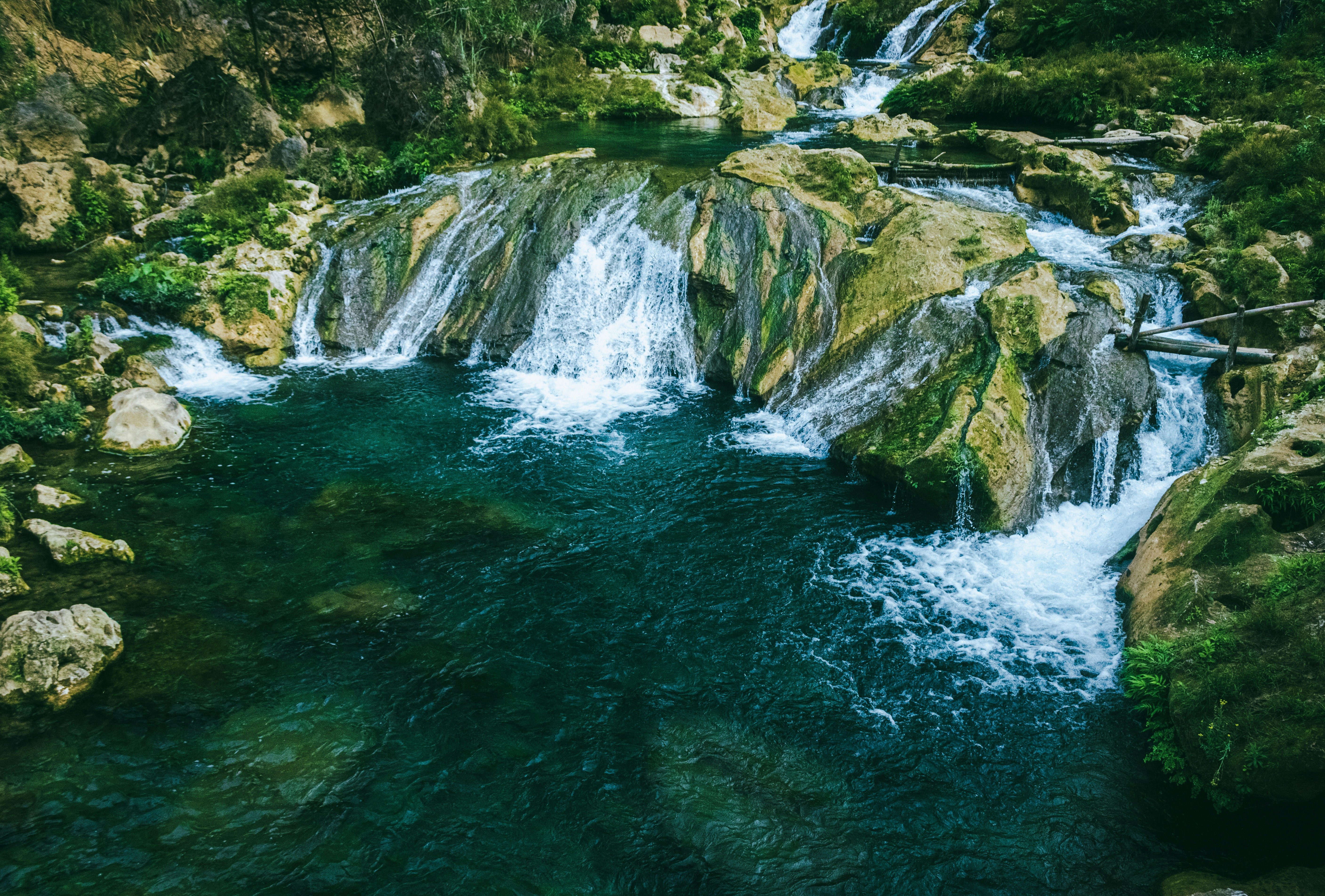 a small waterfall in the middle of a forest, 