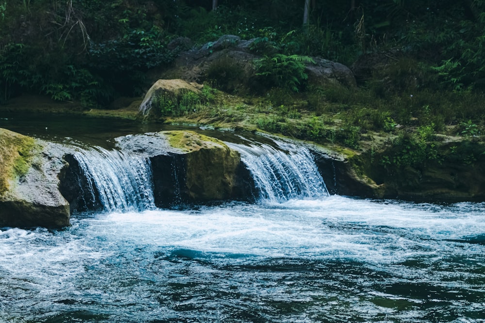 a man standing on a rock next to a waterfall