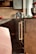 A modern kitchen area features sleek dark cabinets and a countertop with various items. Prominently placed is a red stand mixer, a black coffee maker, a red kettle, and several bottles and containers. The ambient lighting and neutral tones create a cozy atmosphere.