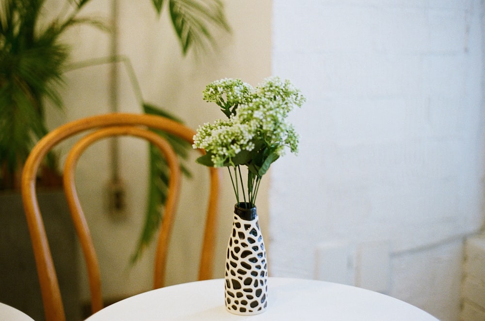 a white table with a black and white vase with flowers in it