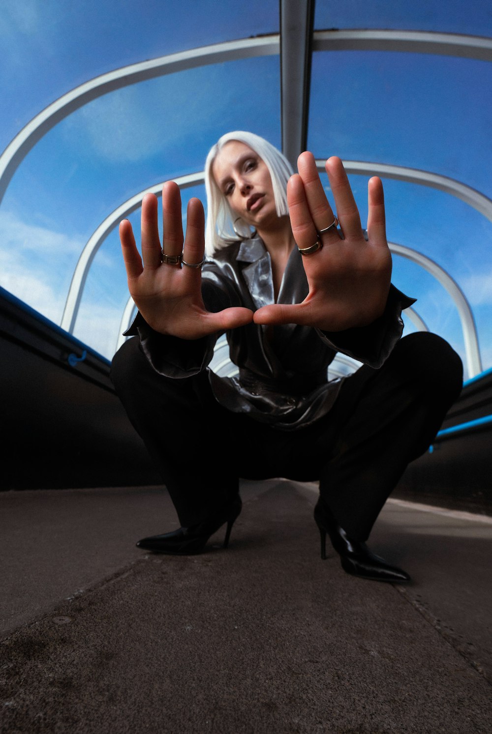 a woman with white hair and black pants holding her hands up in the air