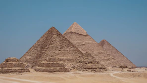 three pyramids in the desert with a blue sky in the background
