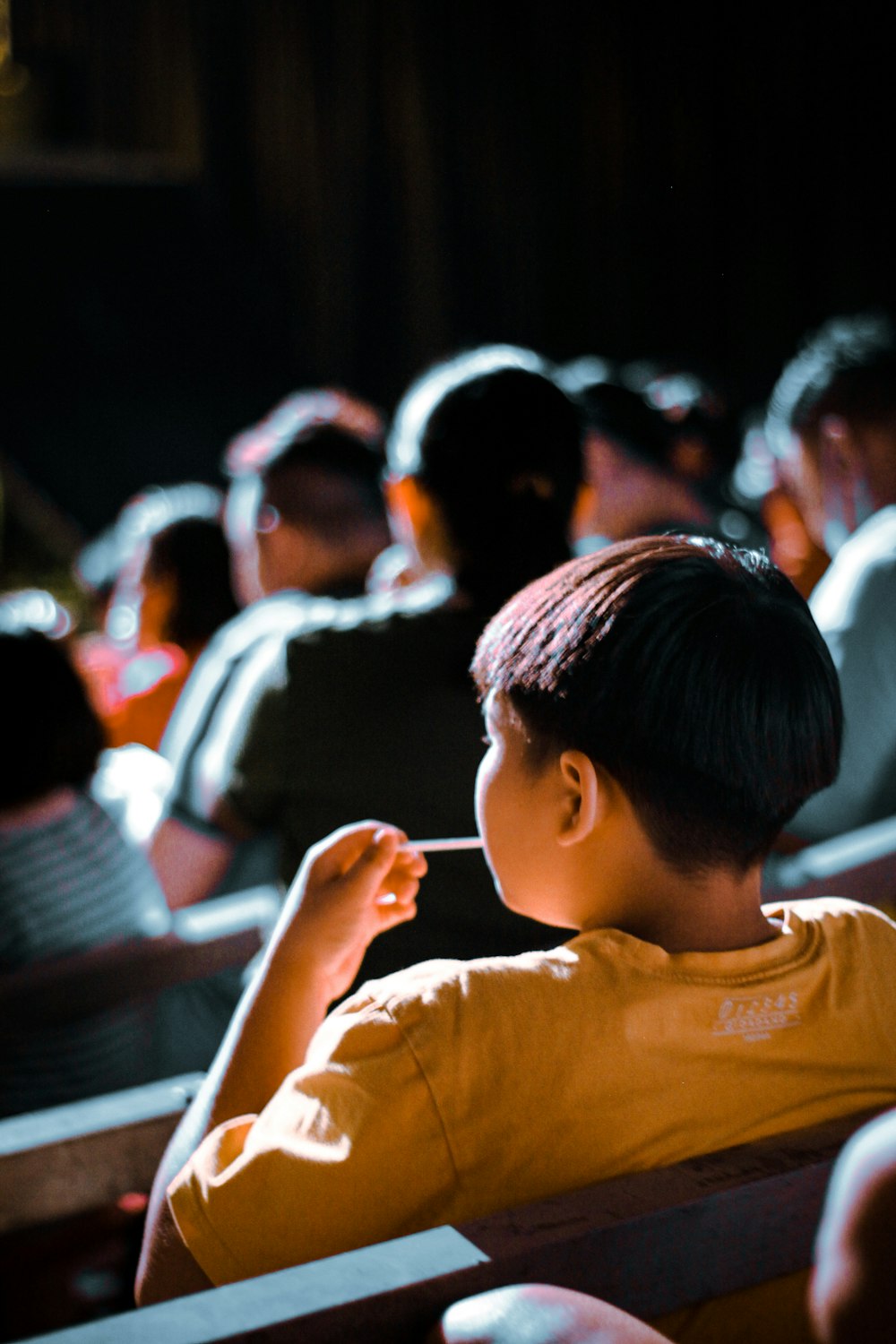 a young boy sitting in front of a crowd of people